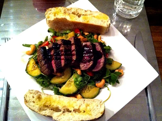 lovely salad topped with a juicy steak and some bread on the side|Richard Koolenさん