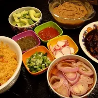 Braised lamb tacos with rice & beans. Accompaniments: pickled red onions, radishes, avocado, scallions, tomatillo salsa & red salsa|Holly Doranさん