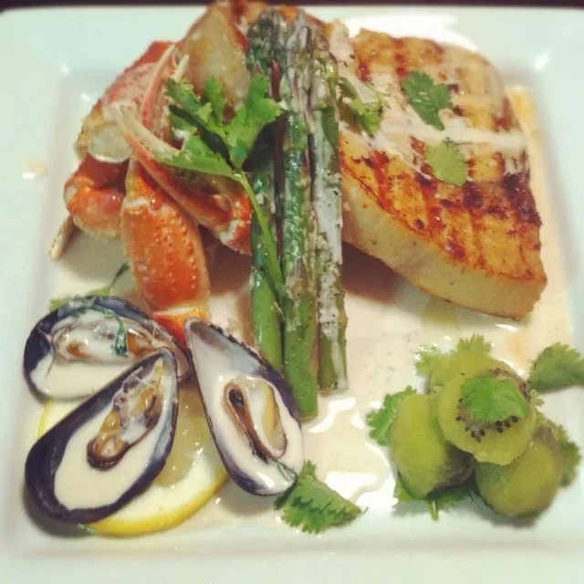 A grilled lemon garlic marinated swordfish, steam snow crab, puny blue muscles and asparagus topped with a champagne cilantro cream sauce and for a light desser|Brian Churchillさん