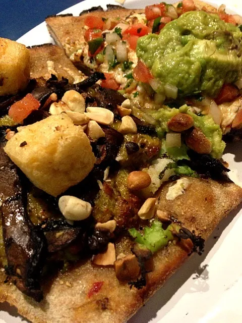 Organic pizza dough with half peanut curry, coconut rice, mushrooms, peanuts and tofu croutons, and half Daiya vegan cheese, black bean purée, salsa and avocado|georgianaさん