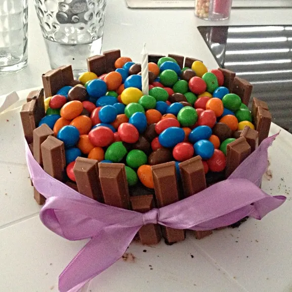 Rainbow cake rounded with kitkat's and topped with thousands of pretty m&m's|janine hartungさん