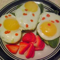 Sunny Side up eggs and sriracha, spinach leaves, avocado, all on top of toasted slices of cranberry walnut bread|AngelEyesさん