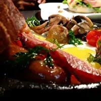 Sunday morning breakfast. Sunny side up, two pieces of bacon, 1 garlic brat, and rosemary sautéed mushrooms and tomatoes with a large slice of white sandwich br|Charlotte Thomasさん