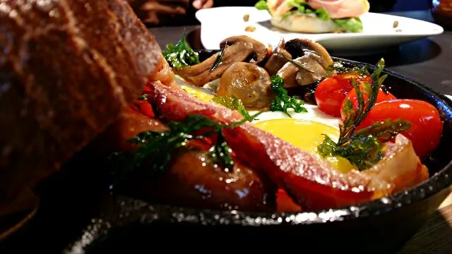 Sunday morning breakfast. Sunny side up, two pieces of bacon, 1 garlic brat, and rosemary sautéed mushrooms and tomatoes with a large slice of white sandwich br|Charlotte Thomasさん