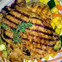 Grilled pork chops seasoned with fresh citrus oranges picked from our tree, garlic, fresh garden picked thytme and oregano top of a bed of veggies (carrots corn|maile nunezさん