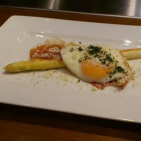 鉄板焼ホワイトアスパラ、生ハムエッグ  春野菜で北海道のアスパラを丸々焼いてもらい、軽く火を通した生ハム、削りチーズの掛かった半生の黄身を崩して頂きます。|akiponさん