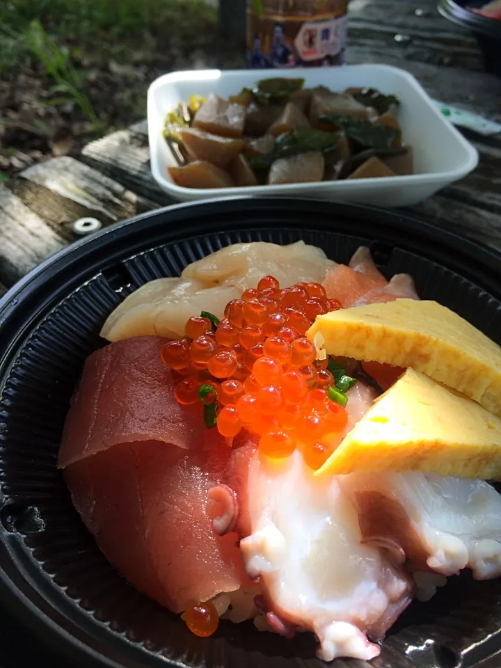 Snapdishの料理写真:公園の木蔭のベンチでお昼ご飯。スーパーの海鮮丼と、こんにゃくとピーマンの煮物。|liccaさん