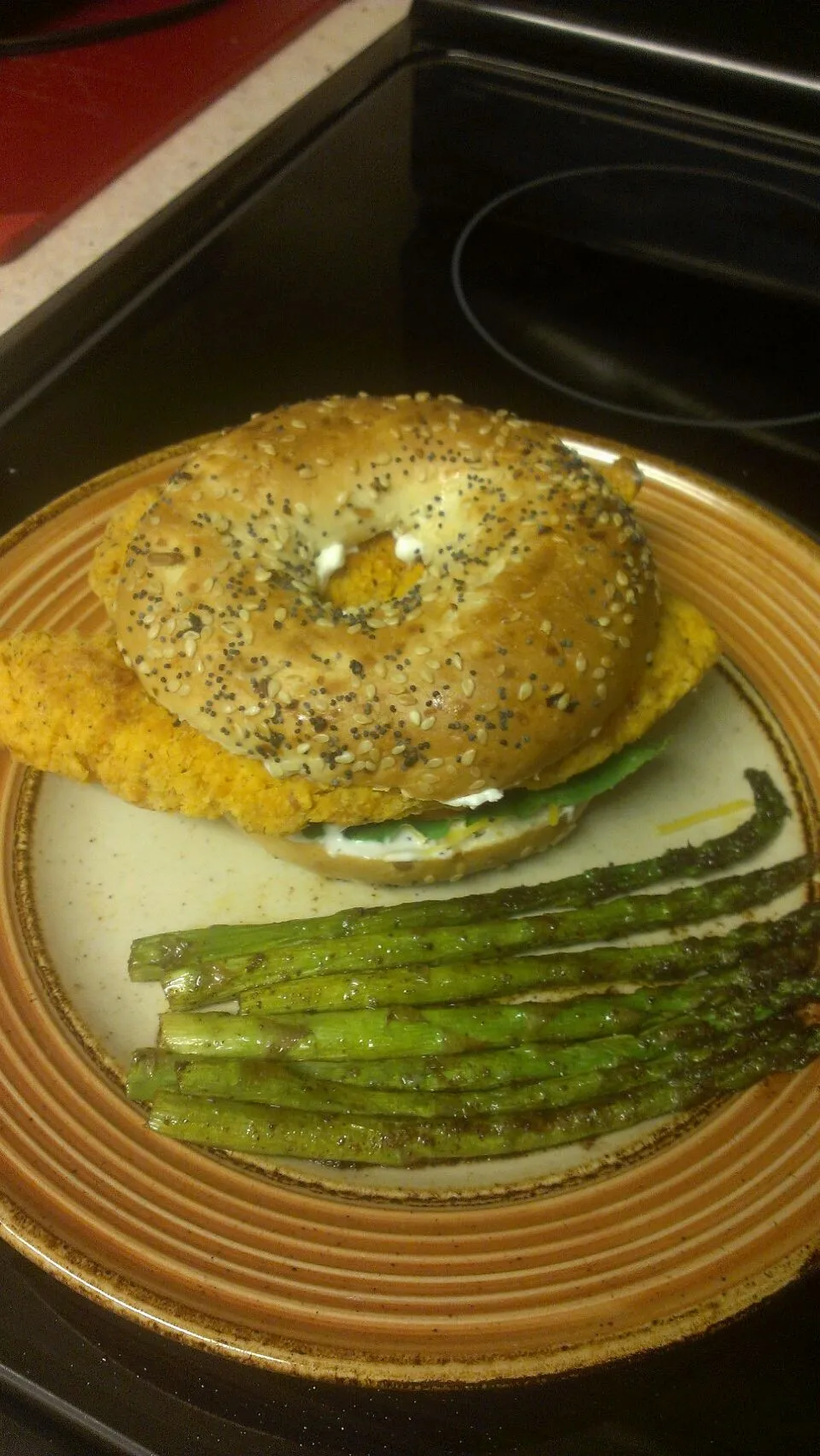 chicken strip bagel sandwich with asparagus on side.|Brandonさん