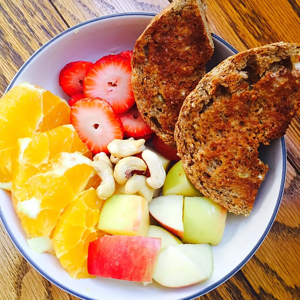 Fruit bowl: oranges, strawberries, apples, and cashews with a toasted sprouted whole grain bagel with earth balance spread|victoria valerioさん