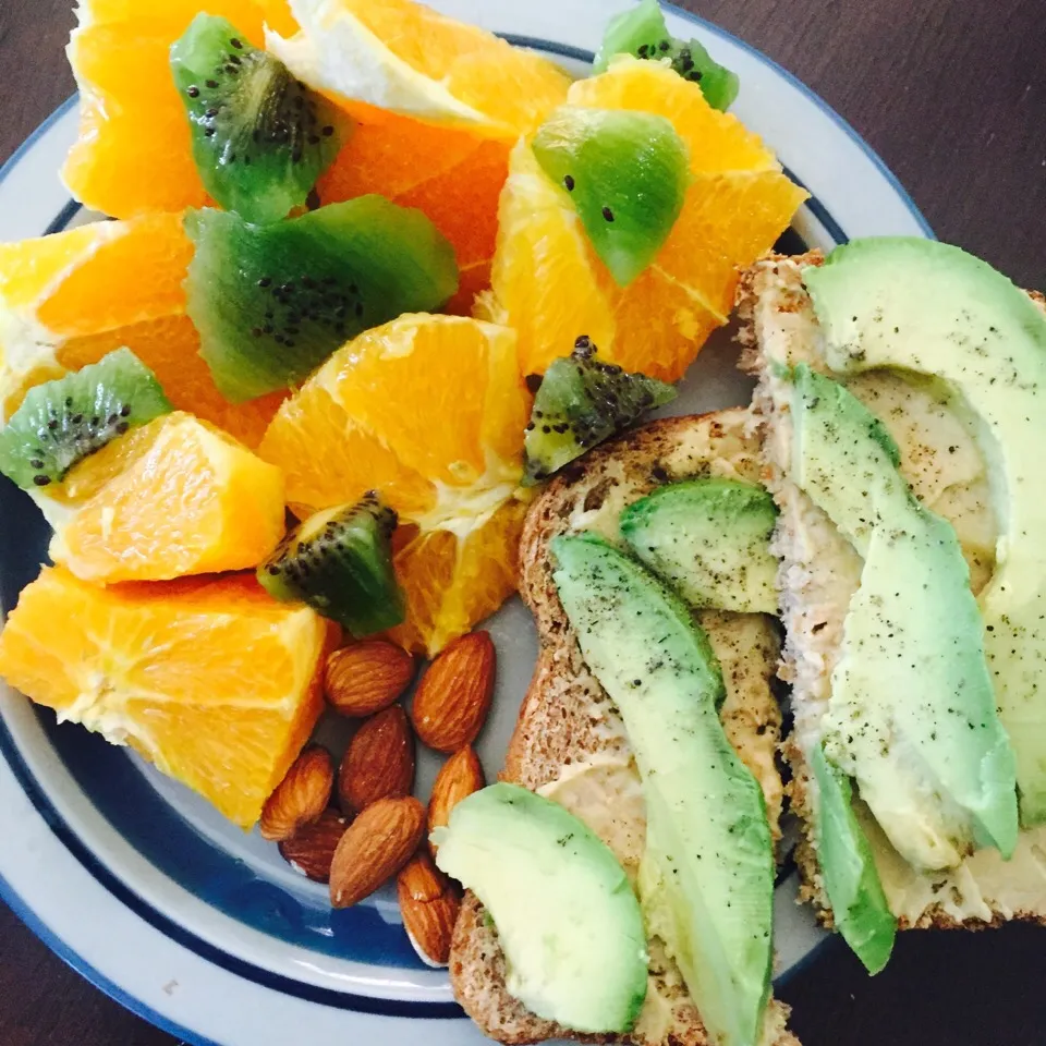 Ezekiel toast with hummus and avocado paired with almonds, oranges and kiwi slices|victoria valerioさん