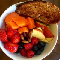 Fruit bowl with strawberries, apples, berries, papaya and almonds with fresh artesian multigrain toast with earth balance butter