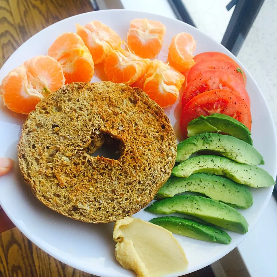 Sprouted Whole grain bagel with hummus, tomato, and avocado and two tangerines|victoria valerioさん