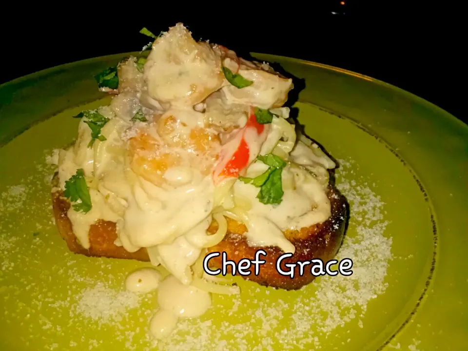 Garlic bread with Alfredo seafood pasta on top|grace flambertさん