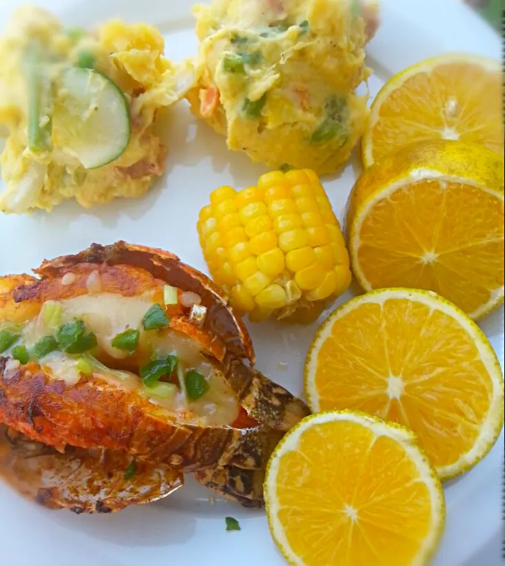 fried lobster tail stuffed with pepper jack cheese, Chinese potato salad , corn and garnished with sliced orange|Alicia Kimaliさん