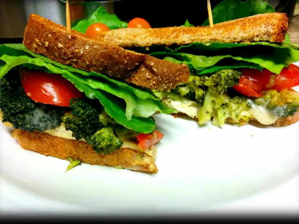 Baked crunchy tofu topped with a roasted garlic broccoli pattie held together with oaxaca cheese and finished off with lettuce, tomatoes, onions and vegenaise o|Violet Floresさん