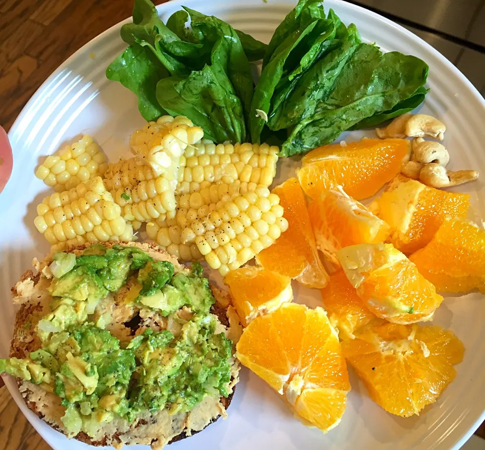 Sprouted whole wheat bagel with hummus and avocado, spinach, corn and oranges|victoria valerioさん