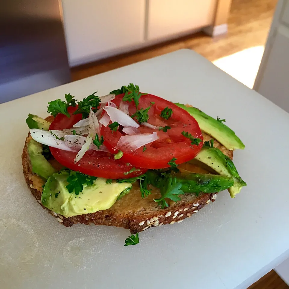 Whole wheat bread with homemade hummus, avocado, tomato and onion sprinkled with cracked black pepper and salt|victoria valerioさん