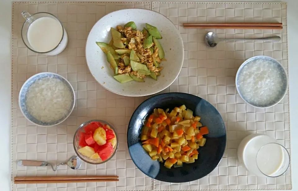 Breakfast for an adult and a kid: congee, fried cucumber with egg, fried potato carrot and onion with curry sauce,  watemelon, soy milk and milk|Liciaさん