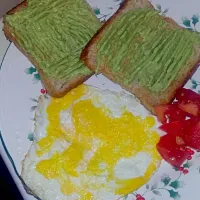 Breakfast. Pan toasted bread with black pepper and avocado mash, attempted sunny side up and a bit of salty tomatoes.|belloさん