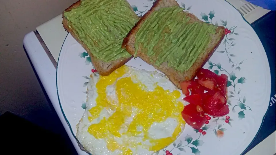 Breakfast. Pan toasted bread with black pepper and avocado mash, attempted sunny side up and a bit of salty tomatoes.|belloさん