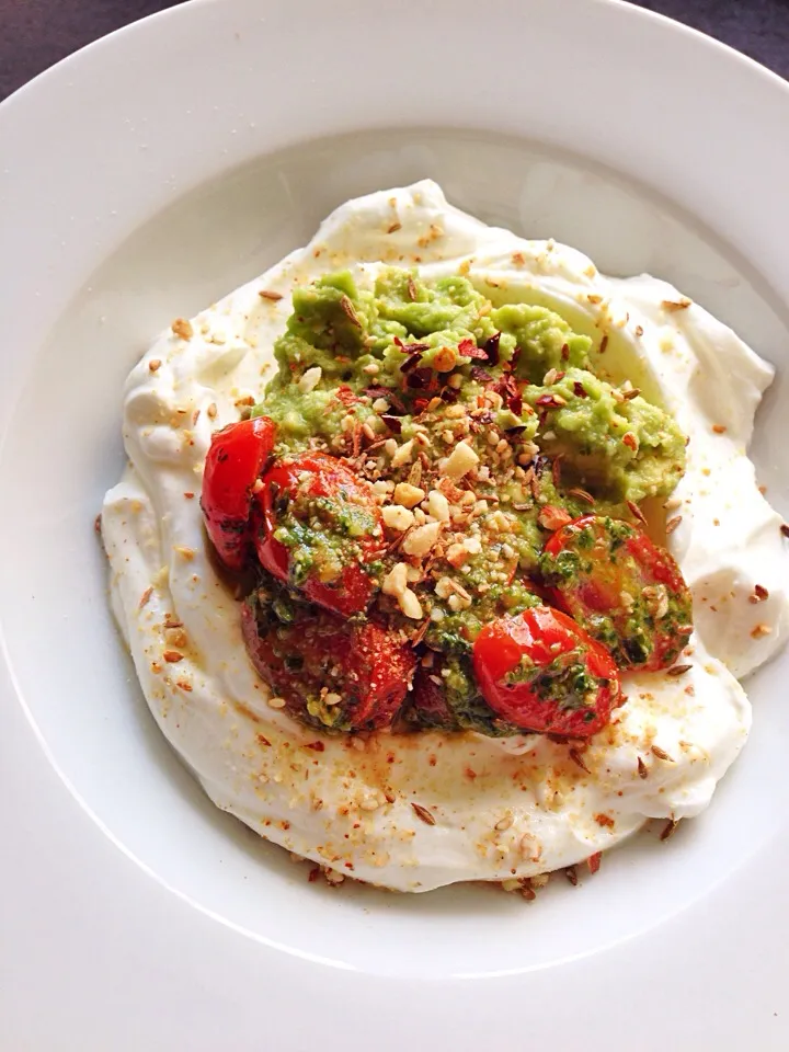 Greek yogurt with pesto-tossed cherry tomatoes, guacamole, dukkah & chili flakes|coxiella24さん