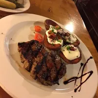 Thick-cut sirloin steak from lava stone grill with stuffed potatoes grilled on an iron plate