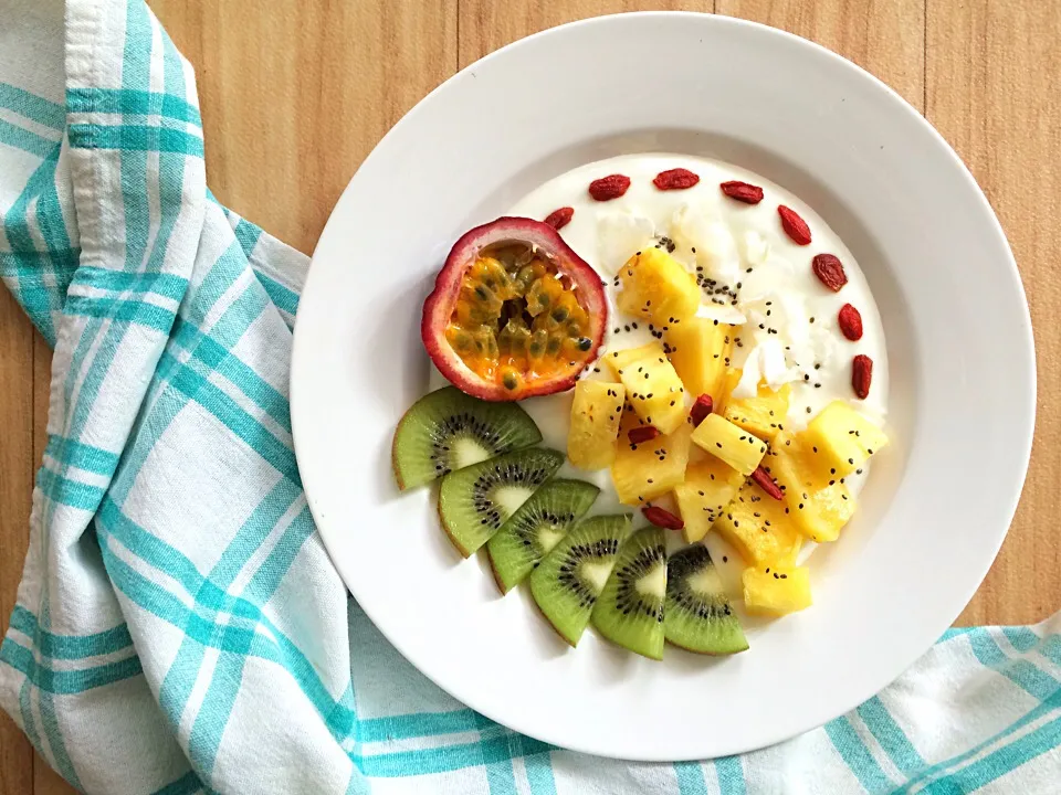 Breakfast bowl with yogurt and pineapple, kiwi, passion fruit, coconut flakes, goji berries and chia seeds.|CatzeMDさん