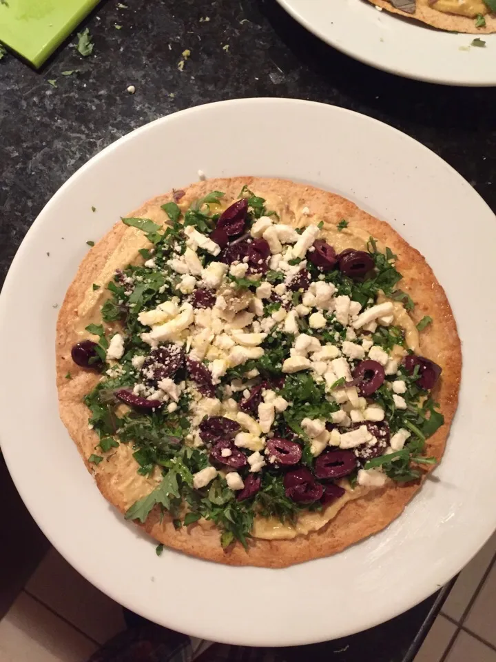 Mediterranean tostada.  Hummus, lemon zest, kalamata olives, feta, olive oil and baby kale on a roasted tortilla.|ernest ristiさん