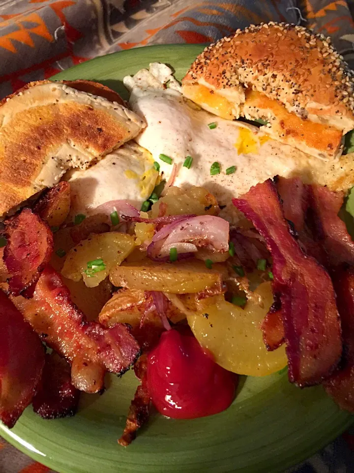 Two eggs over-easy with potatoes, red onions apple-wood bacon and bagel everything|Polly Annaさん