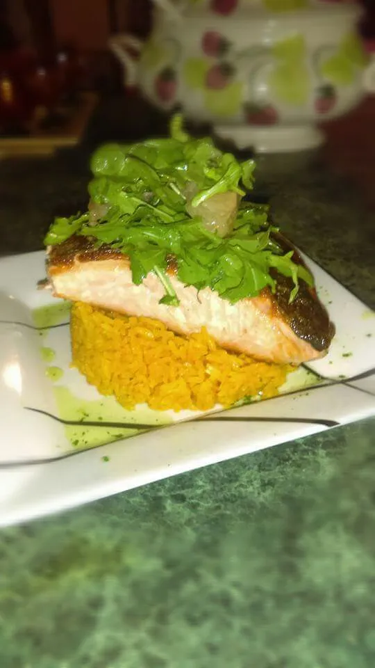 Pan seared salmon with yellow rice topped with a citrus salad.|Derek Ortizさん