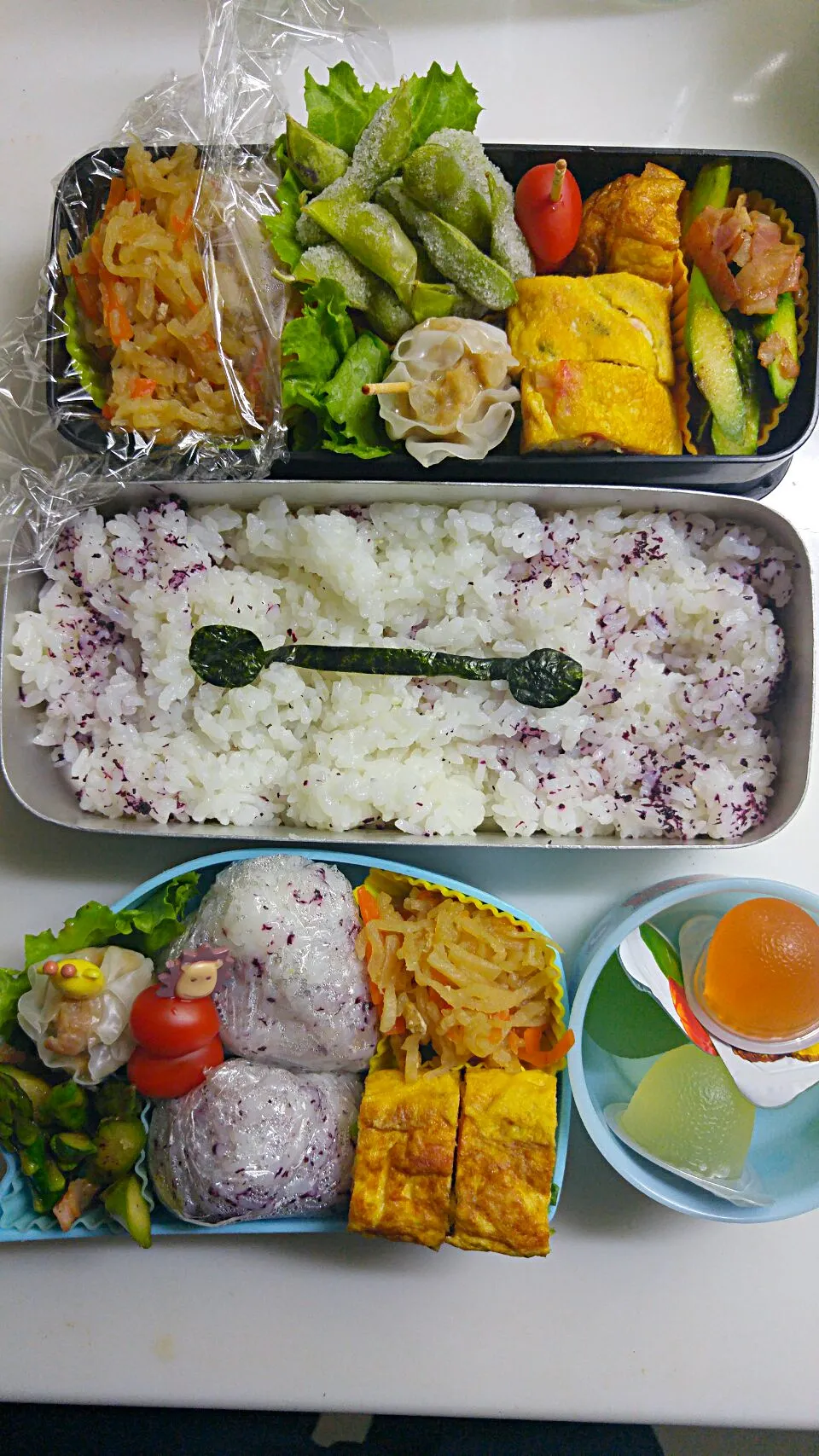 Snapdishの料理写真:☆小２＊春休み☆ゆかりお握り＊カニカマ大根葉玉子焼き＊焼売＊ミニトマト＊切り干し大根＊アスパラベーコン焼き＊ゼリー　夫はついで😁枝豆付き、ちょっとムカつく時は嫌がらせで落書き|ｼｮｺﾗさん