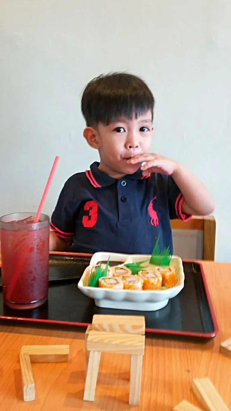 little boy eating maki sushi|marilou araiさん