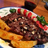 Perfectly grilled ribeye steaks topped with mushrooms and blue cheese; baked garlic/Parm potato wedges and garden fresh tomato/cucumber salad.