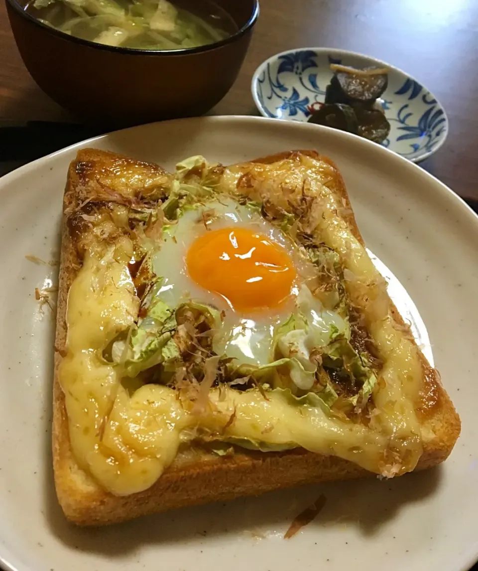 Snapdishの料理写真:単身赴任の朝ごはん☀️🍴
お好み風目玉トースト🍞  焼きそば附属の粉ソースが決め手☝️
キャベツともやしのスープ
きゅうりのキューちゃん漬🥒|ぽんたさん