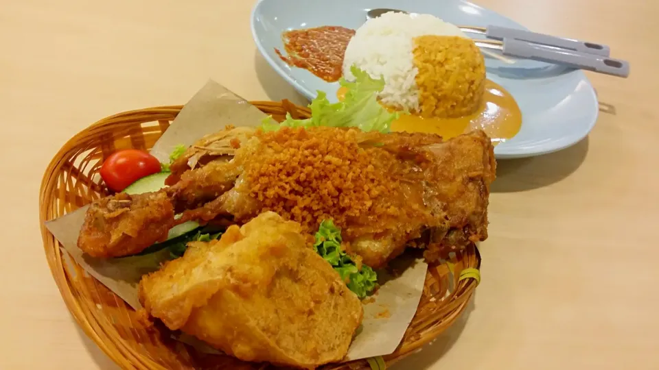 Ayam Penyet (Delicious Indonesian food). It is made up of Fried Chicken, Fried bean curd, at the side are sliced cucumber & tomatoes. White rice is topped with |tracyさん