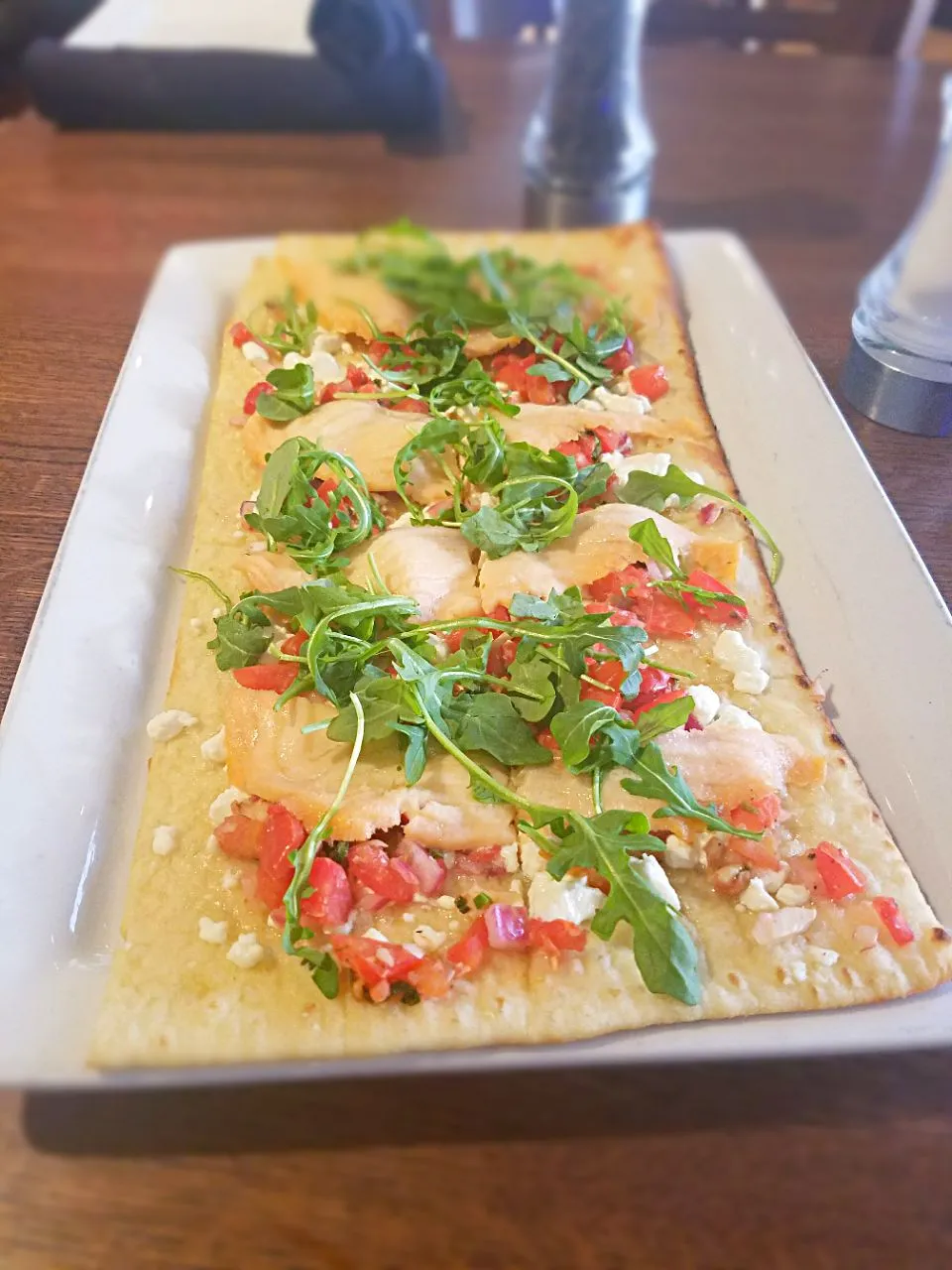 Montreal flatbread. Garlic butter then diced Roma tomatoes, red onions, capers with smoked salmon and then top with arugula|Melissa Greenさん