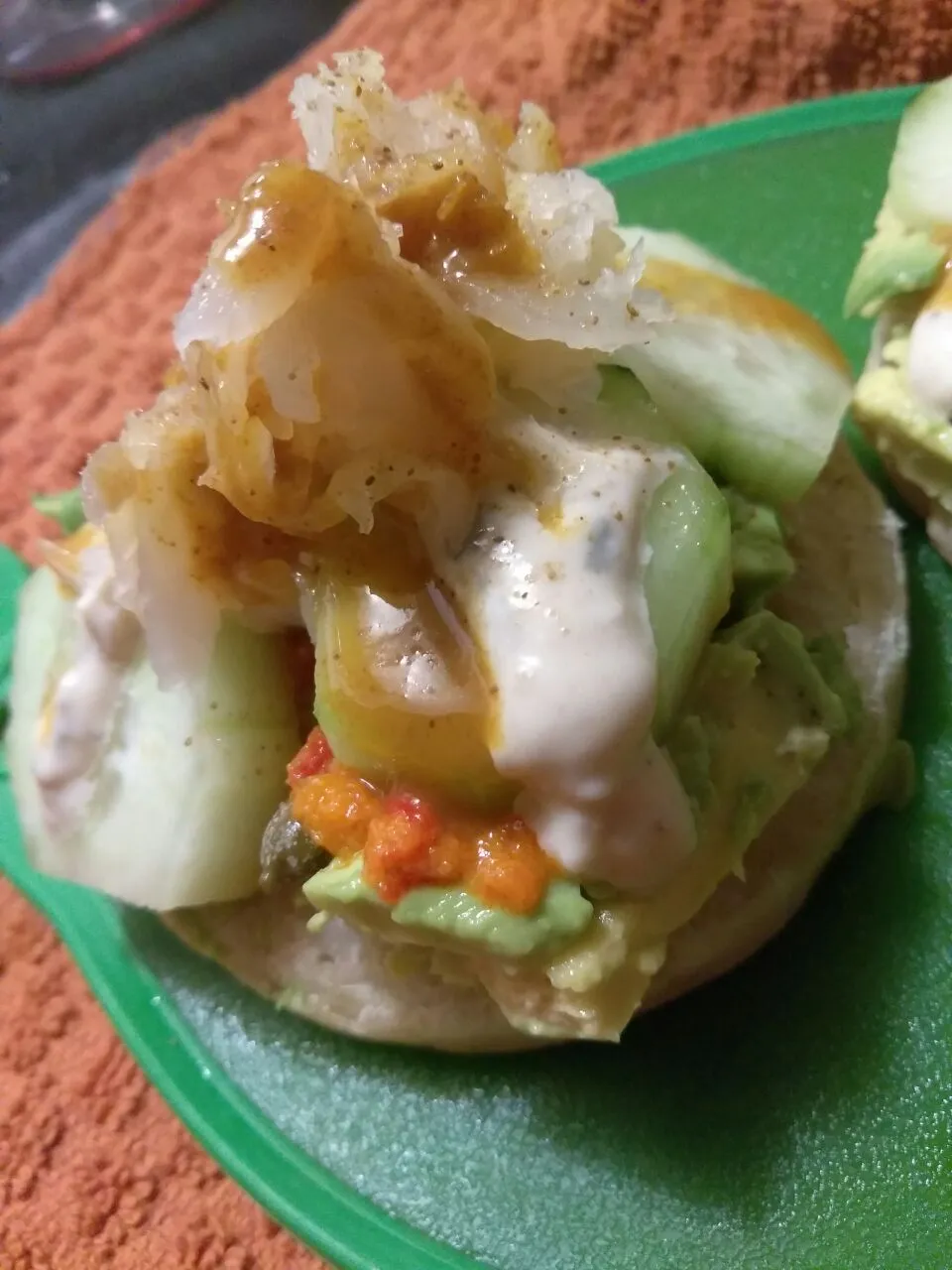 crumpet with avocado, cucumbers, sriracha pesto, kraut, capers, and celery salt.|Polly Gelfusoさん