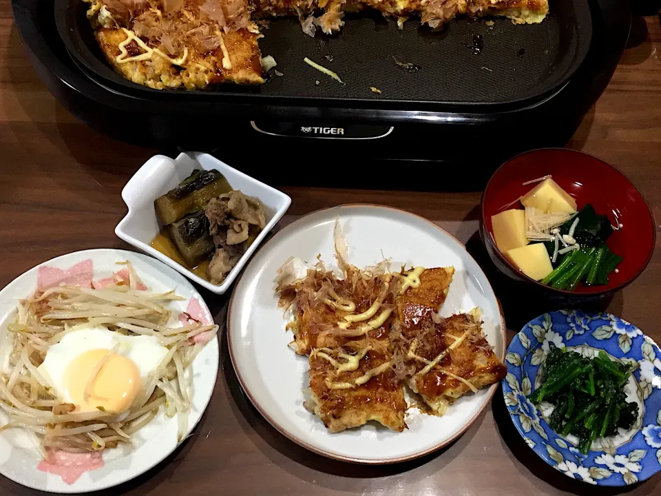 ホットプレート一杯のお好み焼き もやしの巣ごもり卵 ナスと豚肉の炊いたの ほうれん草のお浸し 卵豆腐と青菜のお吸い物|おさむん17さん