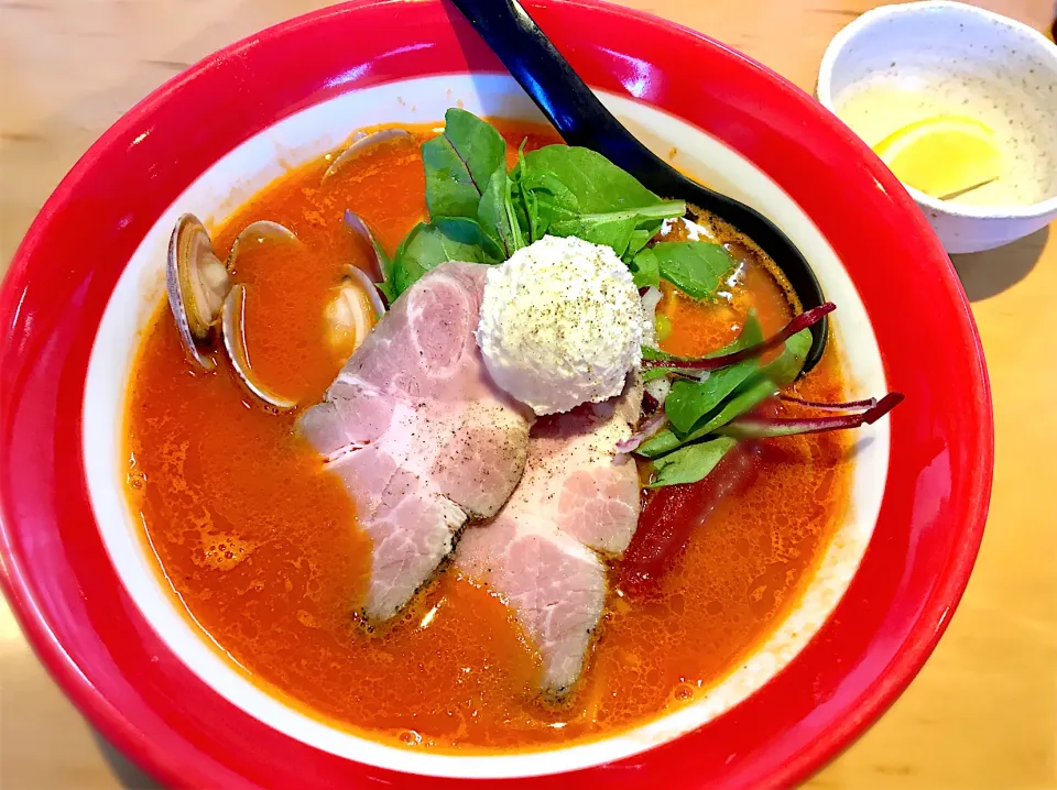 Snapdishの料理写真:トマトラーメン。1年ぶりのご無沙汰メニュー。大きなホールトマト🍅、マスカルポーネ入りクリームチーズ、アサリ、ローストポークのトッピング。添付のレモン🍋とタバスコで味変して最後まで楽しませてくれます❗️|リフルシャッフルさん