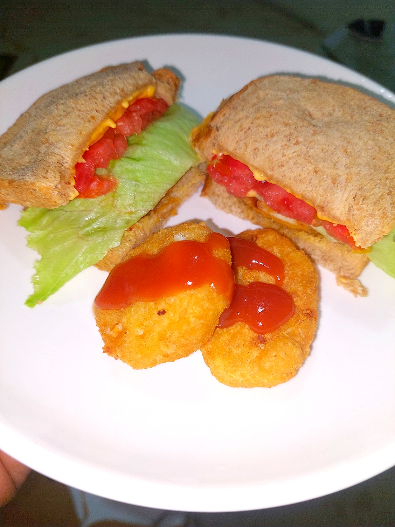 chicken nuggets sandwich 
with lettuce, cheese and tomato.