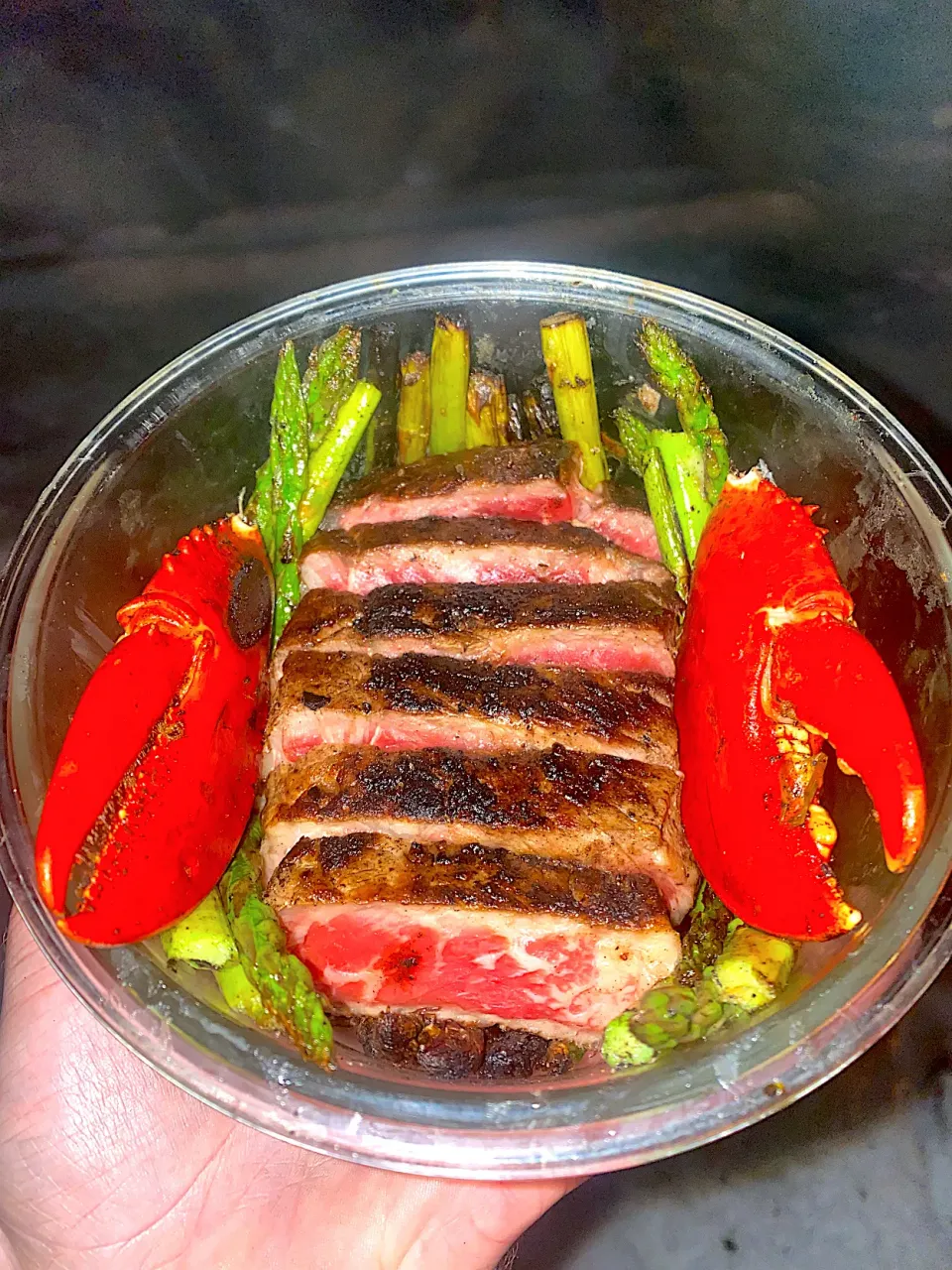 BentoFox's dish Seasoned steak rare, and two beer steamed lobster claws on top a bed of asparagus grilled with garlic butter|BentoFoxさん