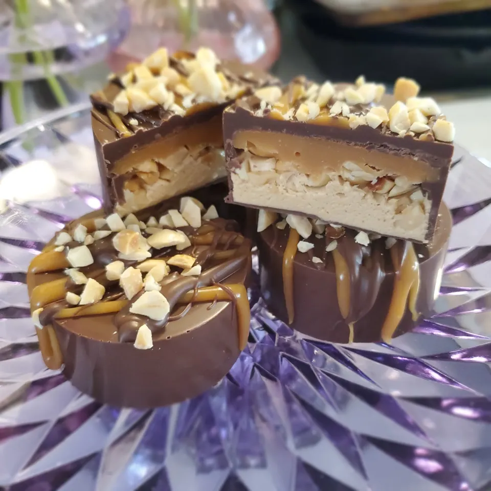 Snickers style pucks with homemade butter caramel and peanut butter nougat, topped with chocolate, caramel, and peanuts|FaeAstrayさん