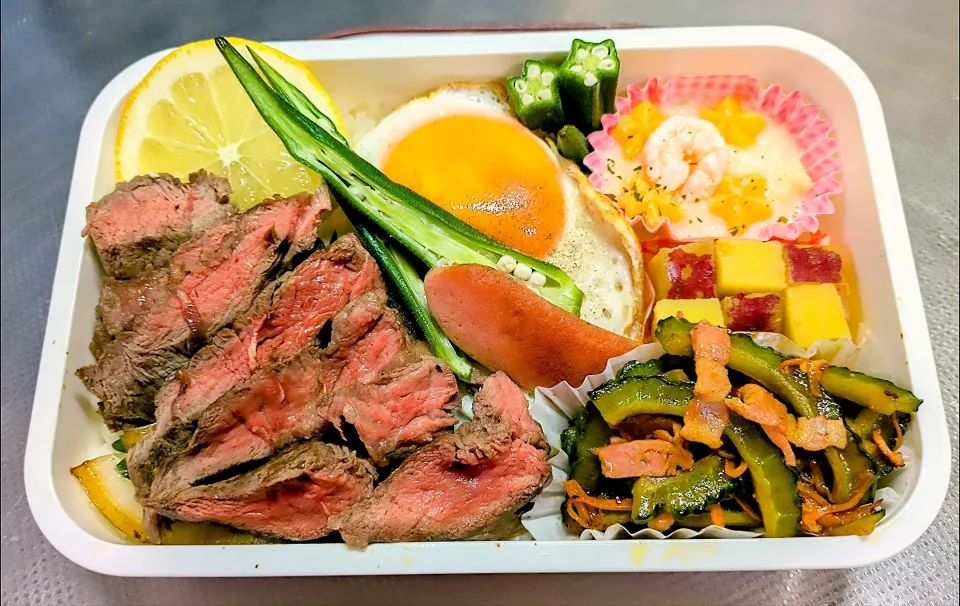 本日の日替わり弁当

①牛ミスジステーキ  オリジナル玉ねぎソース
②海老グラタン（冷食）
③さつまいもレモン煮
④ゴーヤー・人参炒め
⑤目玉焼き
⑥1/2 ウィンナー
⑦玉ねぎロースト、彩り おくら2種・レモン|TakeBooさん