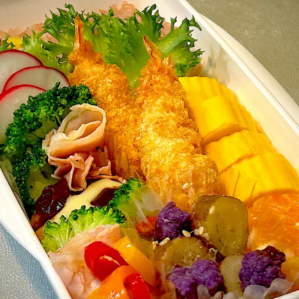 №25 お弁当　冷凍ブロッコリーを緑は薄切りにし、紫は小さい房になるように朝から真剣に切ったみたのだが、そこには当然触れられず、「黄色多くね？！。」というひと言に、いや、卵焼きが好きでしょと返してみたが、卵焼きも🍤も🍊も黄色で括られていたコトガ判明する。オ、オレンジ色だよっと思ったが、言わずもがな。ピンク色をと思い生ハムを焼いてまで入れもうした今日のお弁当各色フルコンボぐらいに思ってたが、ガクッとした朝。（青色は保冷剤で補っていることを書いておく。）|こげちぃさん