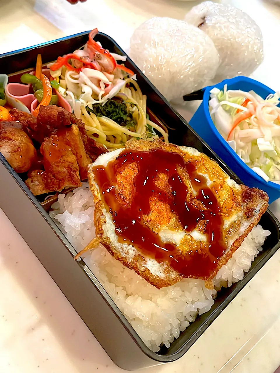 おっさん弁当　サラダ　にんじんピーマンしりしり　ニンニク　きゅうりの辛子漬け　唐揚げ　パスタ　目玉の親父　キャベツ　おにぎり|ひげおやじさん