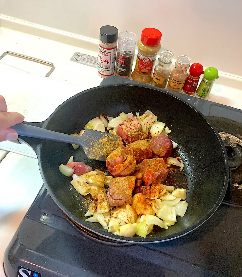 今日の晩ご飯⑤  タジン鍋がないので、いつものフライパンにたっぷりのオリーブオイルをひき、玉ねぎ、ニンニク、唐辛子を炒め、香りが立ってきたところで塩胡椒した山羊肉を投入し、クミン、コリアンダー、ローリエ、パプリカ、シナモンを振り、さらに炒めます。|なびさん
