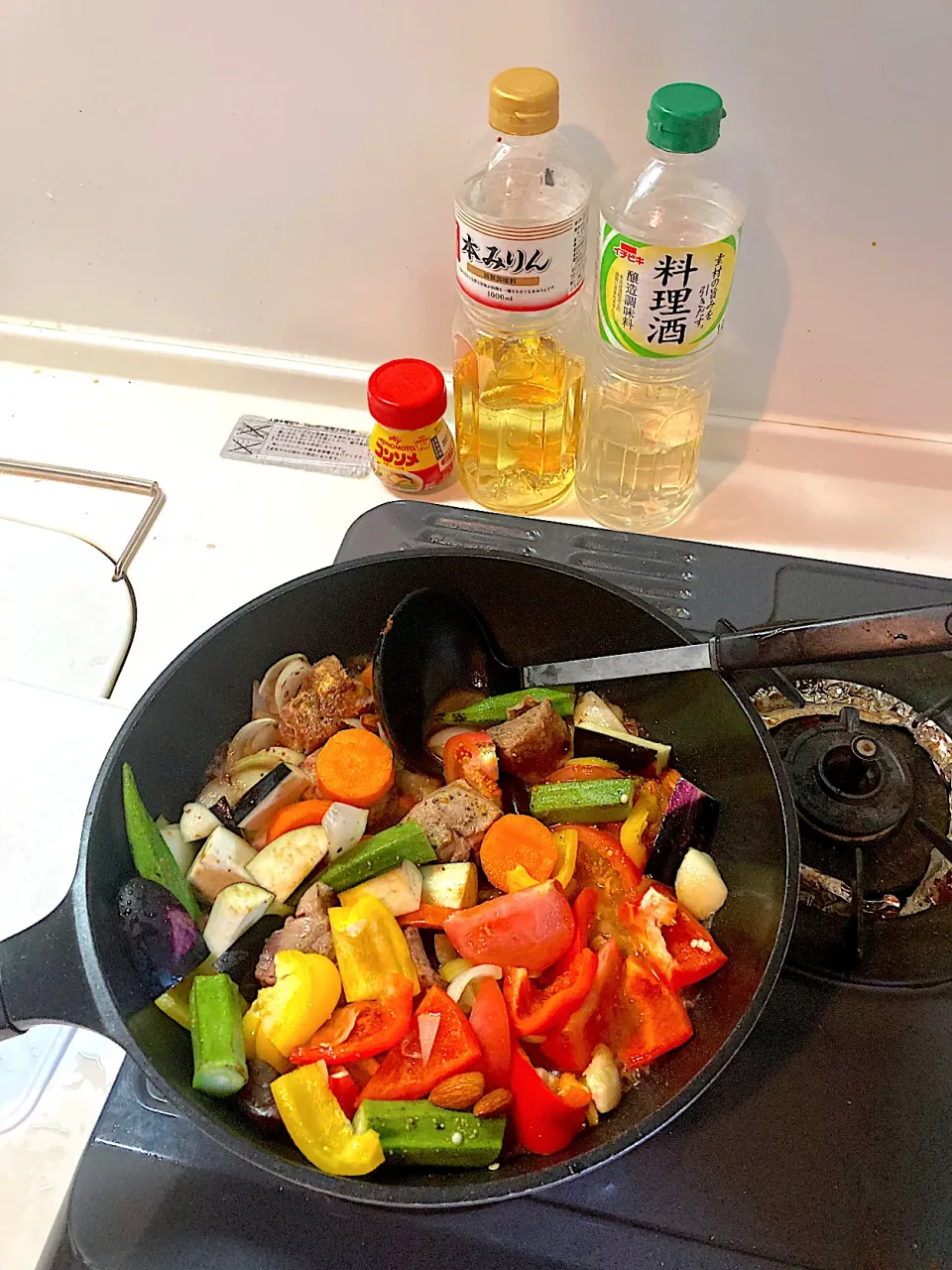 今日の晩ご飯⑥  トマト、赤パプリカ、黄パプリカ、茄子、オクラ、ブラックオリーブ、デーツ、アーモンドを投入し、コンソメと酒とみりんと水を加えて煮込みます。|なびさん